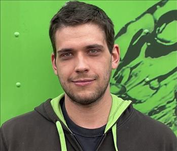 Male employee, brown hair, hoodie, in front of a green background