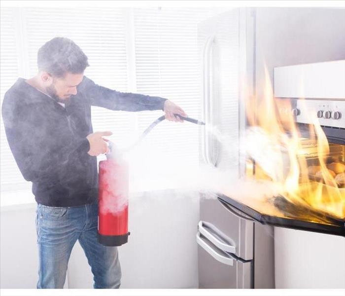 A man with a fire extinguisher putting out fire from an oven.